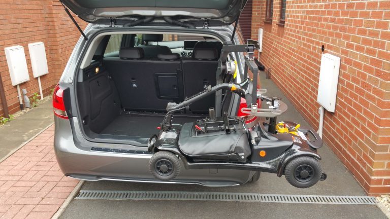 Smart Lifter LM shown lifting a mobility scooter into the open boot of a car.