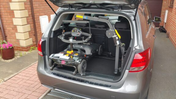 Smart lifter LM hoist shown attached to a mobility scooter in an open car boot.