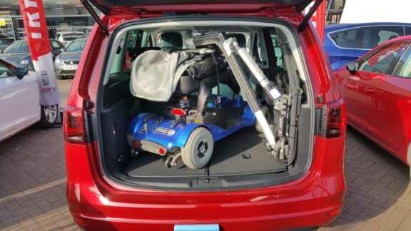 Smart Lifter LP hoist shown attached to a mobility scooter in an open car boot.
