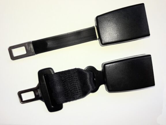 Close up photo of seat belt extensions in two styles against a flat white surface.