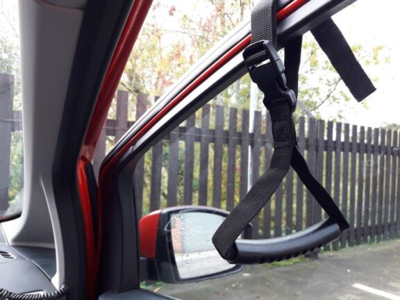 The Car caddie is a simple strap that clips around a car door windowframe with a rubberised grip.