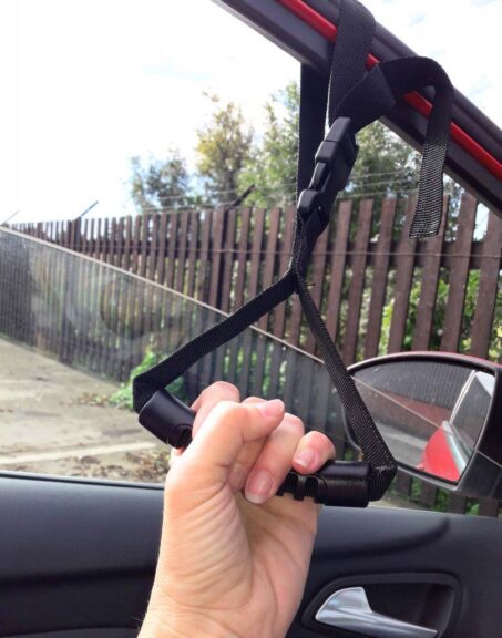 Car Caddie handle attached to car door window frame gripped by a hand.