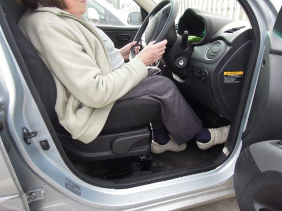 A driver is sat in a car in the raised seat, in a higher than normal driving position.
