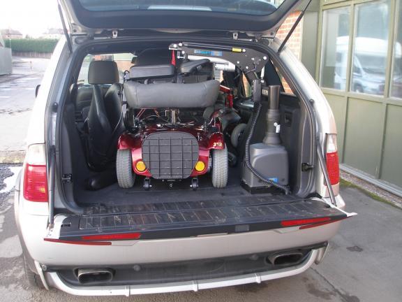 A mobility scooter is next to a Carolift VSL 6900 in the back of an open car boot.