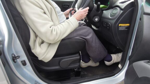 A driver is sat in a car in the raised seat, in a higher than normal driving position.