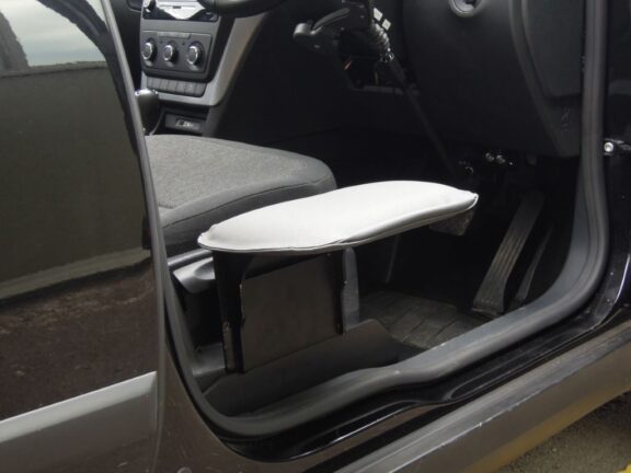Seg Seat Transfer plate shown slotted into place next to the driver's seat, with a smooth padded surface level with the chair.