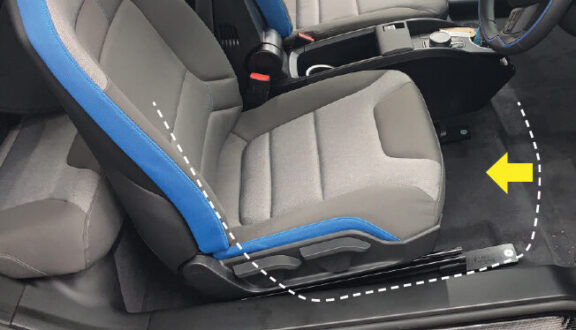 A driver's seat is shown in the furthest back position with extended seat runners, with the backrest all the way up to the rear seat. A dotted white outline indicates where the seat would be able to reach without extended seat runners.
