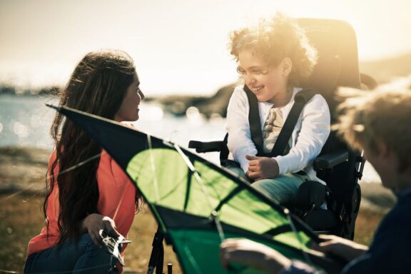 A girl sat outside in a GS seat while playing with some friends and a kite.