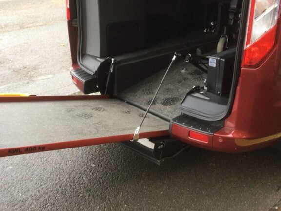 Photo of an Easy Ramp motor unit lowering the embedded ramp in the rear of a wheelchair accessible vehicle.