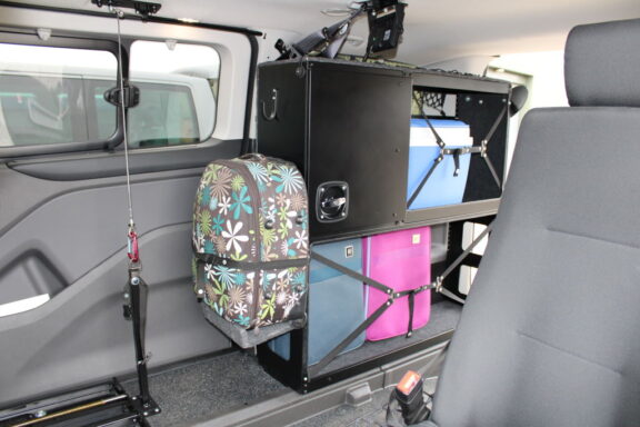 WAV Store shown filled with various suitcases, all strapped and secured to the black shelf unit in the back of a van.