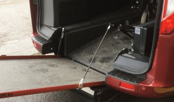 An easy ramp motor unit is shown lowering an in-built ramp of a wheelchair accessible vehicle.