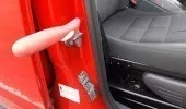 A grab handle fitted to the inside of a red car door to assist with getting in and out of the vehicle.
