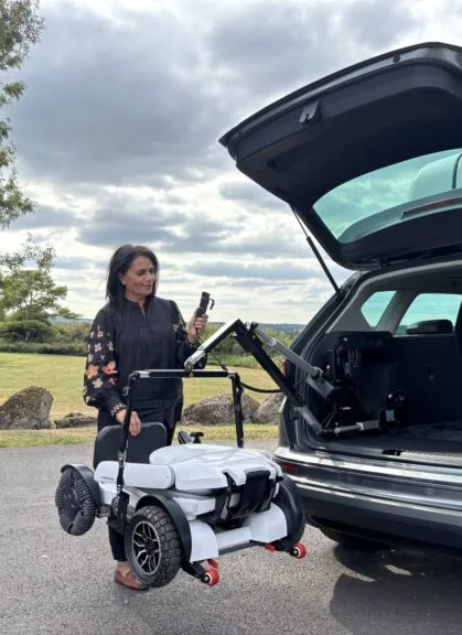 Demo of hoist lifting folding wheelchair into a car boot.